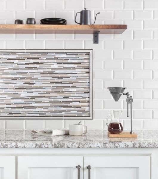 Coffee bar in kitchen with white bevel-edge subway tile and metallic stria accent tile as backsplash.