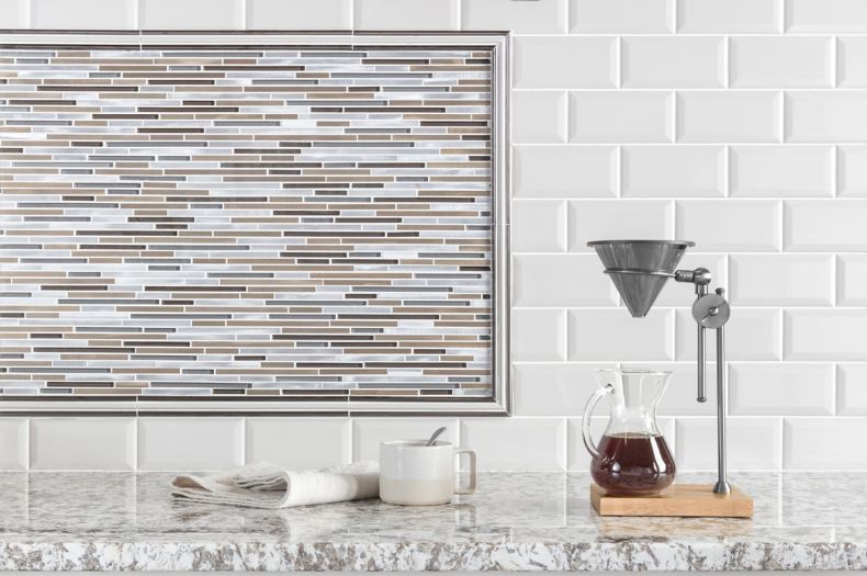 Coffee bar in kitchen with white bevel-edge subway tile and metallic stria accent tile as backsplash.