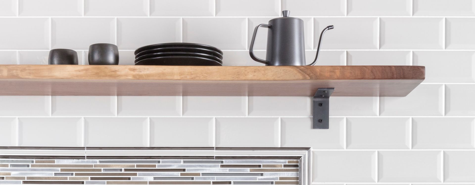 Coffee bar in kitchen with white bevel-edge subway tile and metallic stria accent tile as backsplash.