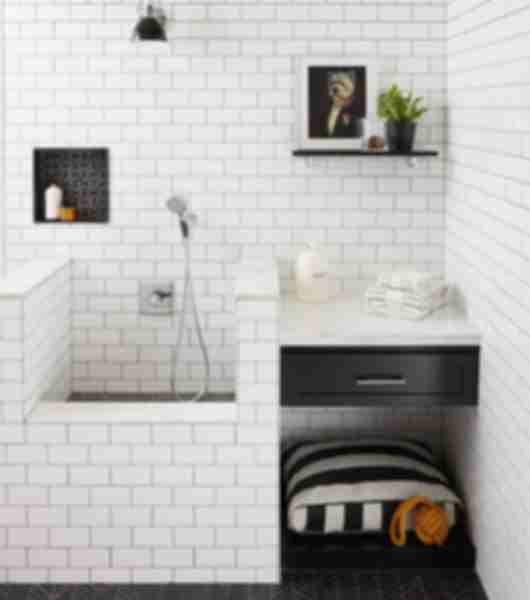 This space is a unique tiled dog washing station done in classic black and white tones but with unique shapes of black tile. Travertine chevron pattern floor adds clean lines and sharp angles this complements the shower pan and recessed niche of a different pattern but same tone coupled with a lighter charcoal/grey element to the design. Marble caps are used on partition walls and classic white subway tile in with black grout complete the look.