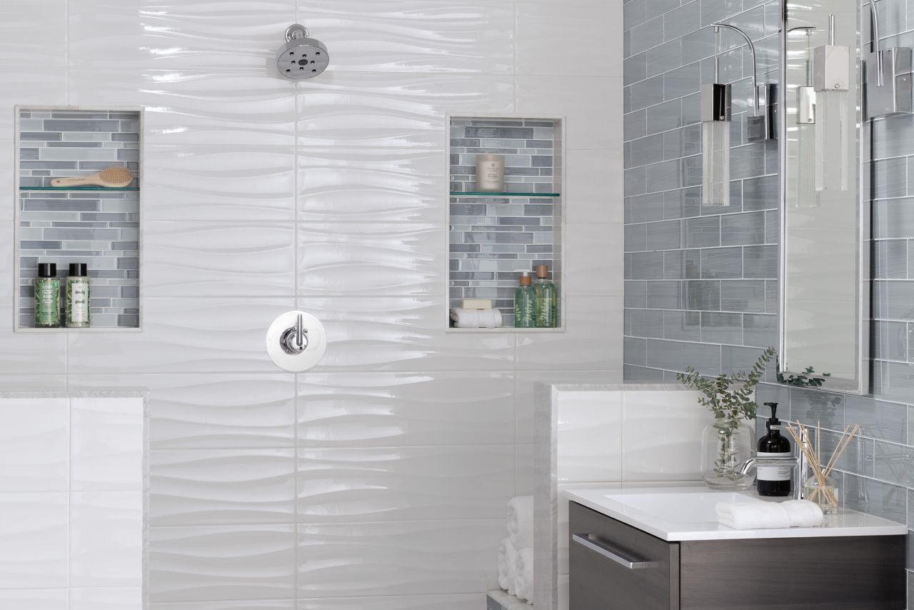 Bathroom area with walk in shower and floating vanity.  Large profile marble look tiles on floor walls are in several sizes shapes and textures.  Shower has two recessed niches with glass shelves glass accent tile that pops off white wall tile. Vanity wall is larger subway to match accent tiles darker color tone and pattern. Shower pan is marble cobble mosaic tile.