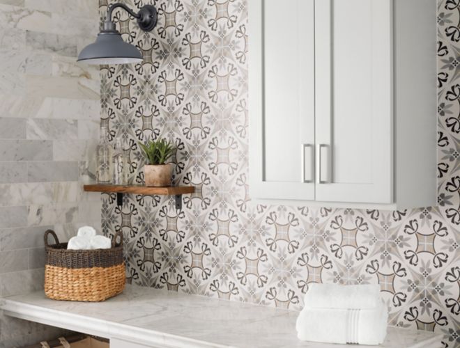 Tiled walls in  white marble tile and a patterned porcelain tile.  Each wall is tiled differently and accents the white marble counter and light cabinets.
