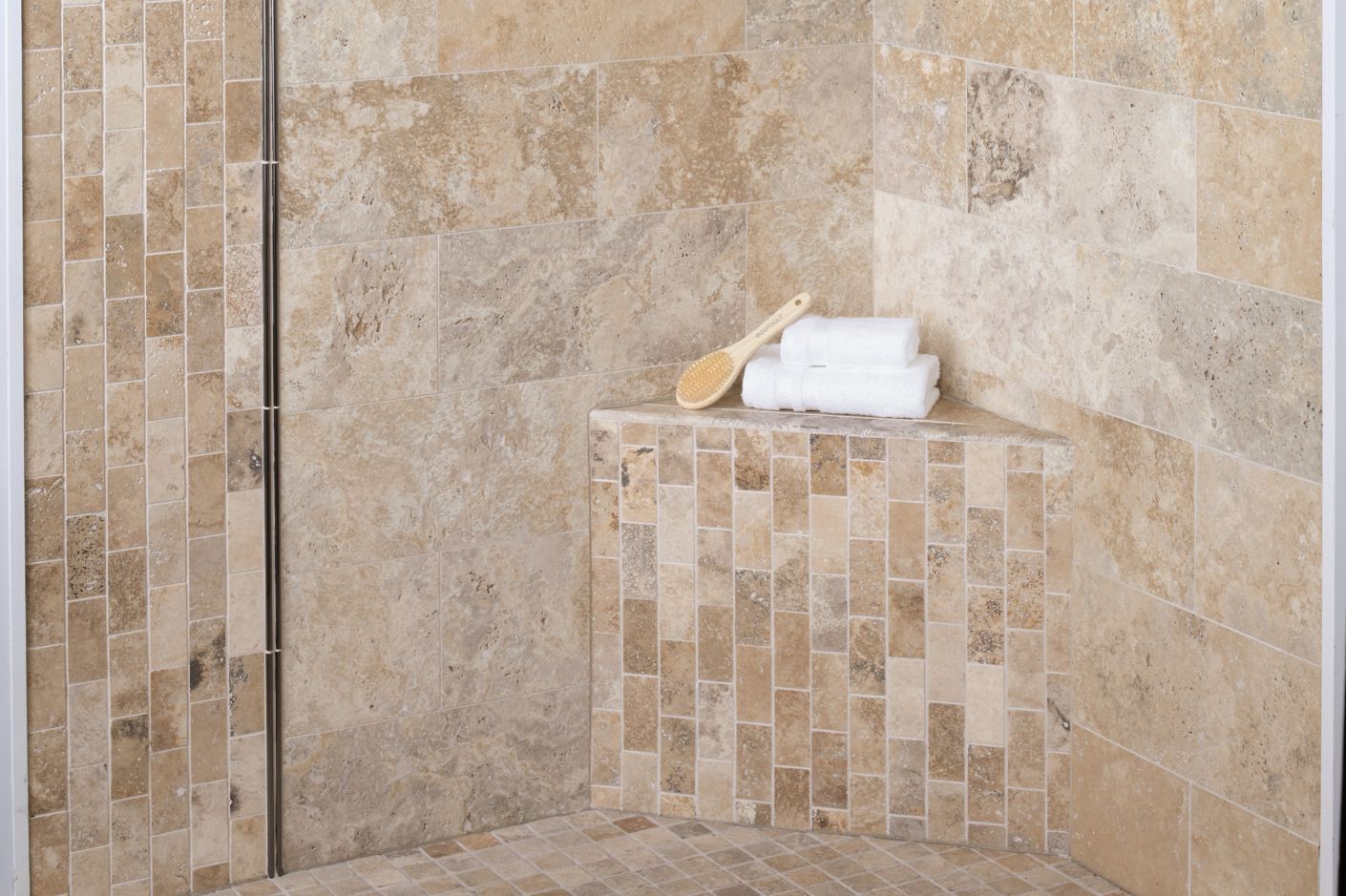 Walk In shower tiled in natural travertine stone with metallic profiles and corner shelves.