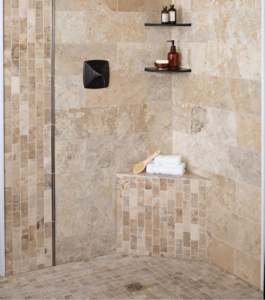 Walk In shower tiled in natural travertine stone with metallic profiles and corner shelves.