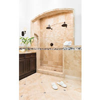 Thumbnail image of Bathroom area tiled in natural beige travertine stone with onyx and glass listello and and floor accecent.  Double shower heads in walkin shower and several sizes and patterns bring interest and flow to this space.