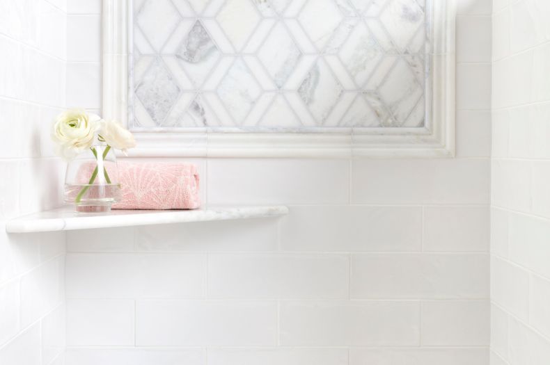 Feminine shower with white marble mosaic and white subway tile.
