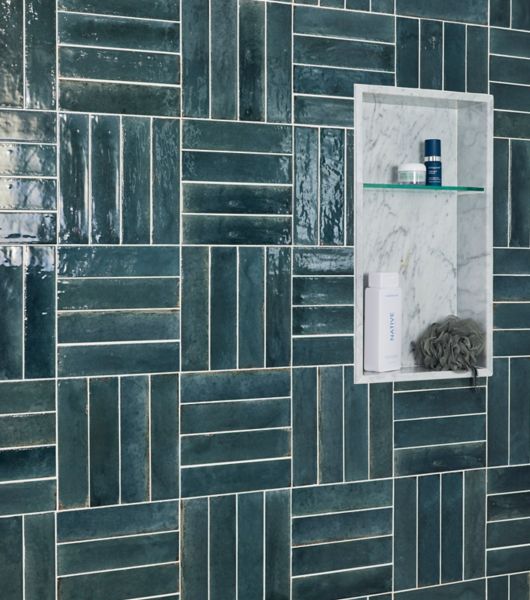 This blue shower features handmade-look subway tile in a grid-stack pattern with a marble shower niche. 