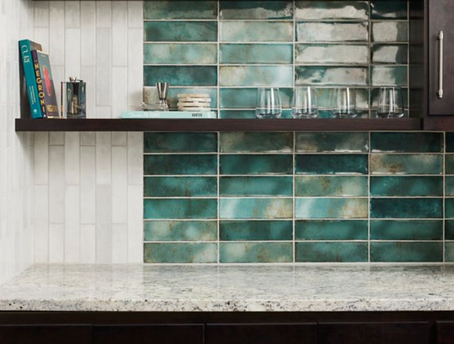 A bar backsplash that features white and green handmade-look subway tile.