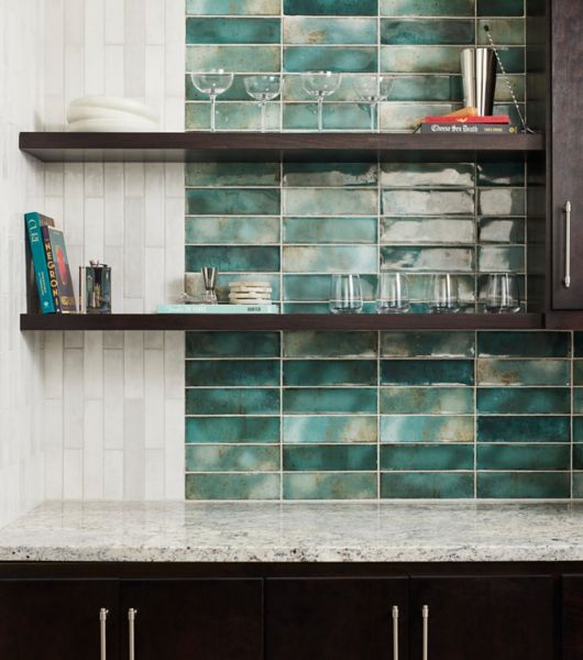 A bar backsplash that features white and green handmade-look subway tile.