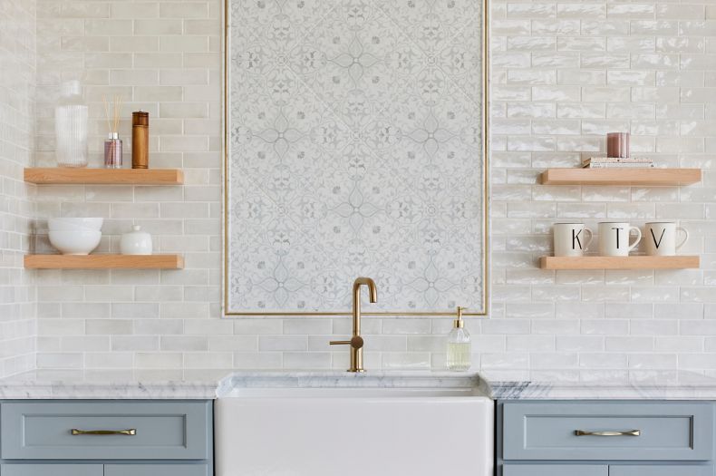 This kitchen backsplash features a white handmade-look subway tile and an ornate patterned tile in a picture frame.