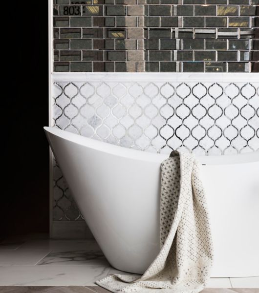 White arabesque and mirror subway tile in bathroom with elegant freestanding tub.