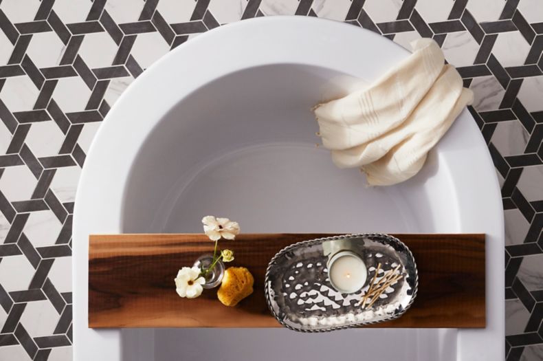 Black and white hexagon-shaped, marble-look floor tile in bathroom with freestanding tub.