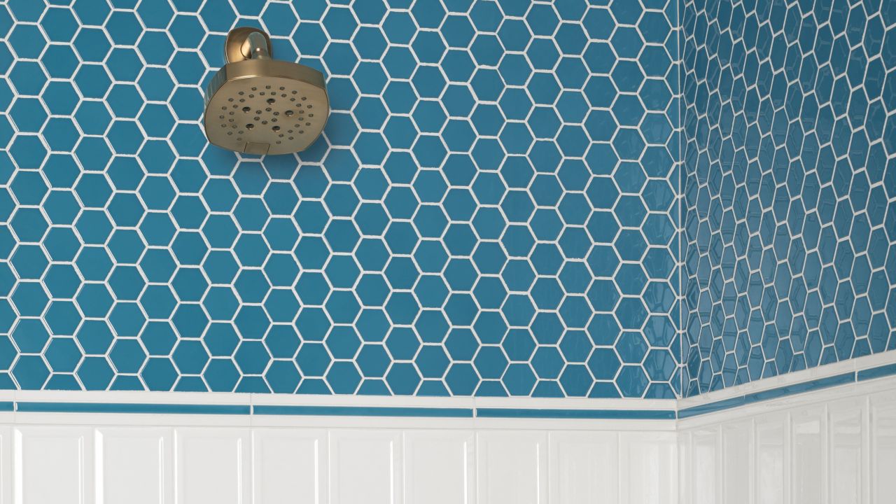 Vertically ran framed subway tile creates the design on the lower shower walls.  Transitioned by white and blue ceramic square pencils the upper walls are a blue 2