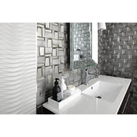 Thumbnail image of Bathroom area with focus on the vanity and wall tile wall tile vanity area has a decorative glass and stone mix glossy tile in a unique design and pattern to really bring impact to the space paired with a textured large format white field tile and a simple Chrome transition dividing the two this area really showcases simple colors yet the look of pattern and texture to make an impactful space the space is mid century modern fixtures and vanity uses clean lines a beveled mirror but the area is softened with lamp type lighting on each side of mirror this space is a statement to be enjoyed for years to come.