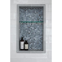Thumbnail image of Featuring a detailed view of a shower niche 14 by 24 in size split in thirds with a glass shelf this niche is used for storing item in the shower area as seen here and is accented with grey penny round mosaic tile with a variety of shades.  Double gloss ceramic grey pencils border niche and white textured gloss subway tile is the wall tile here.