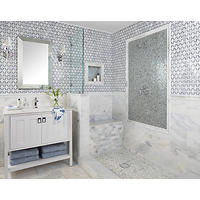 Thumbnail image of Bathroom with walk in shower featuring natural stone- marble- tiles in cool tones of greens Grays Blues whites and ivory's make up the bottom half of the walls and all profiles -in this bathroom a variety of mosaics makeup the shower pan shower bench and wainscoting shower walls above the large format tiles a picture frame around mixing valve is made of glass translucent neutral tones with soft pastels and a metallic finish fixtures are in Chrome.