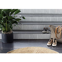 Thumbnail image of Entryway with stairs using flamed granite as the cap and the stair face is a ceramic square tile with  metallic desigin over white background entryway landing  is a faux marble pattern with black background and white marbling. A potted plant, shoes and travel bag are stored here and a woven rug is on landing.