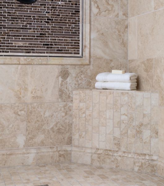 Tan marble shower with white towels.