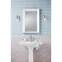 Thumbnail image of Bathroom area with wainscoting behind pedestal vanity two different tiles are used here although they are in the same family one features a pattern the other is a neutral subway tile in taupe with a coordinating chair rail to divide the lower and upper wall tile lower tile is staggered horizontally upper tile is stacked with blue patterned. A bbeveled edged mirror hangs above pedestal vanity and a warm metal is used on fixtures and coupled with glass features.