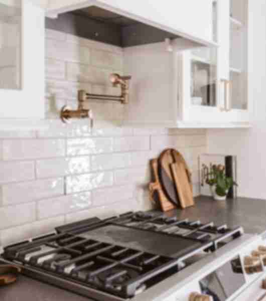 Stove and counter top with white tile backsplash and white cabinets