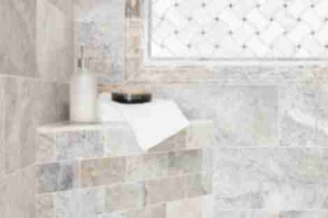 Travertine and marble corner seat in shower.
