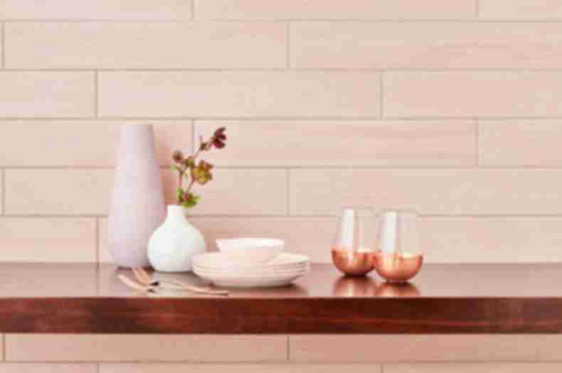Blush pink wood-look wall tile in kitchen with feminine dishware.