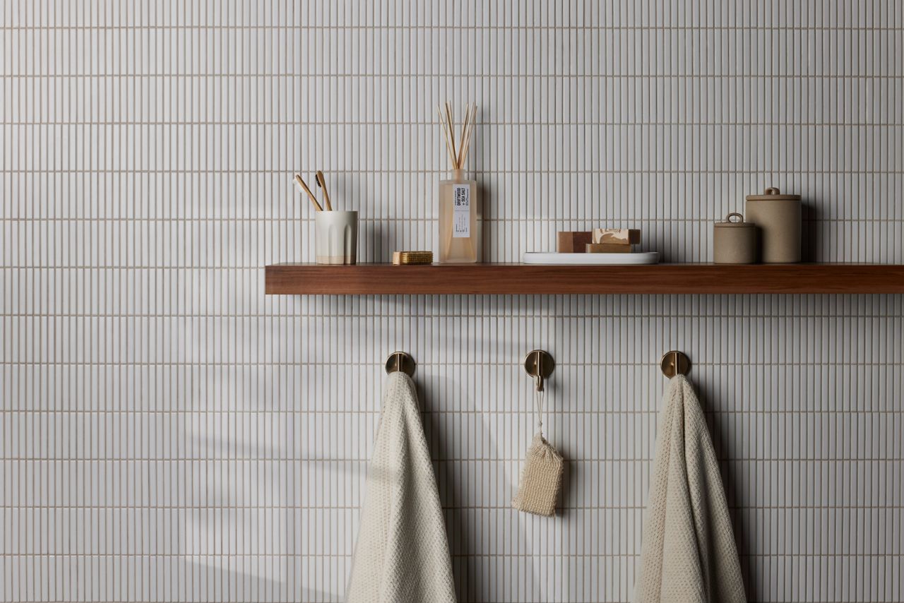 Tiled bathroom wall featuring white thin, elongated mosaic tile that imitates a kit kat shape.