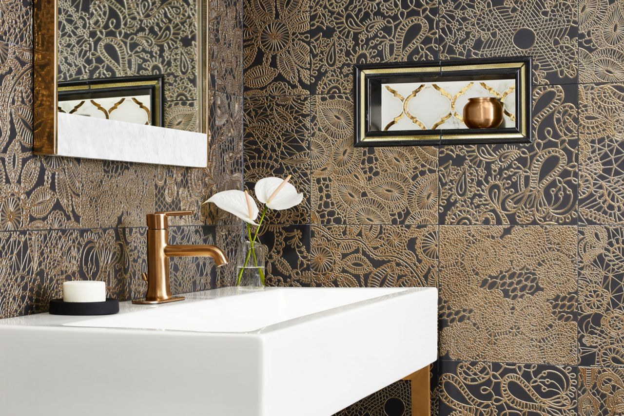 Vanity area with gold and black accent field tile stacked and a decorative niche with mirrored and natural marble tile and like trim tile profiles.