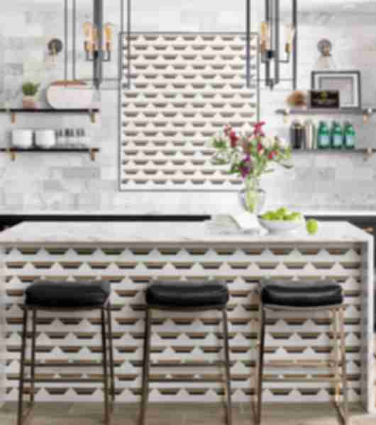 Island area with counter and tile focal wall complementing bar front.With wood-look porcelain combined with clean white carrara marble combined with geometric design adding clean, classic colors. 