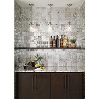 Thumbnail image of A bar backsplash using 12" x 12" mosaic tiles  with a three -dimensional design, highlighted by a metallic silver finish offering a range of textures, incorporating modern lines, tumbled stone and softer touches.