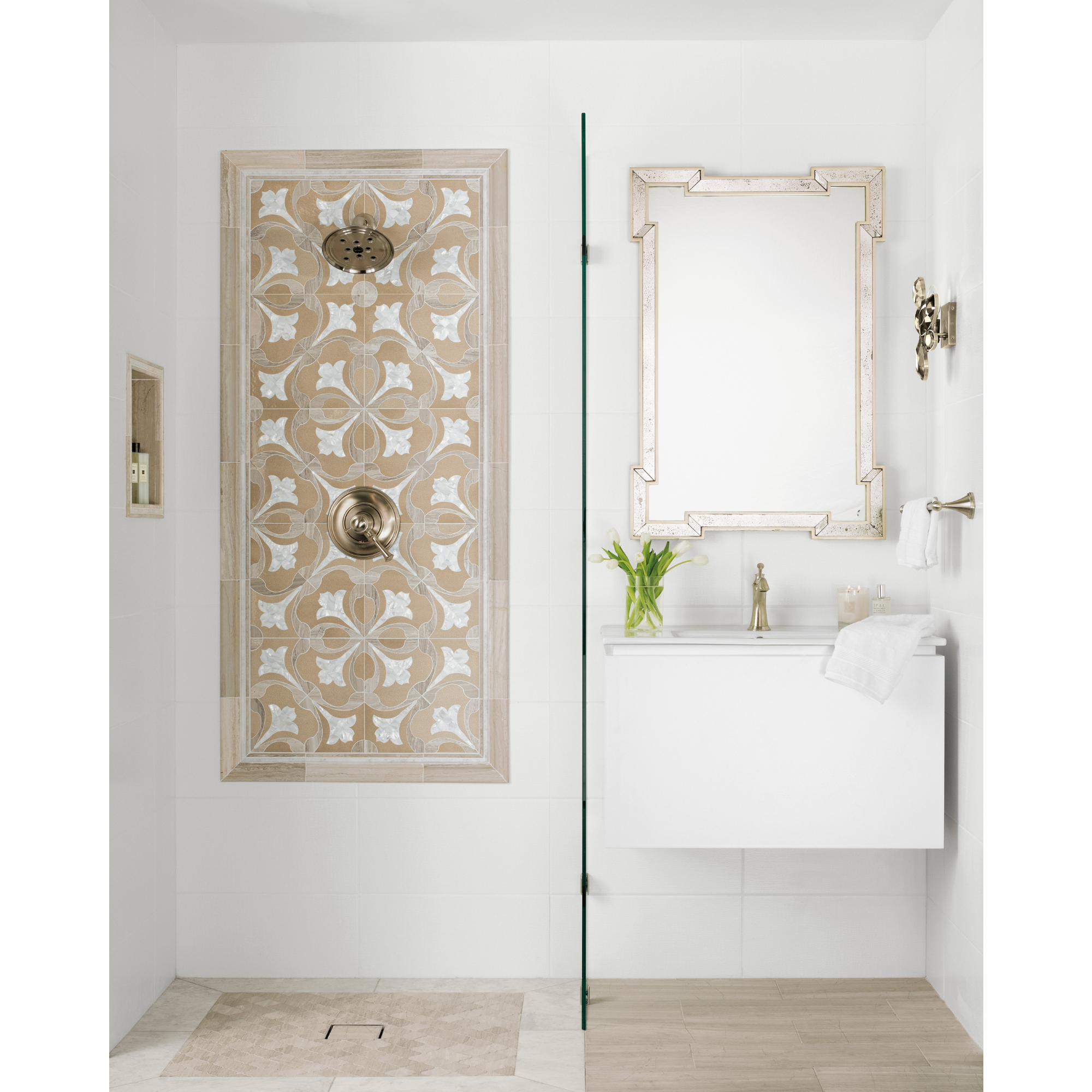 Bathroom area with walk in shower and floating vanity.  Shower and wainscoting tile are rectangular raised glaze white surfaces . Shower wall has a framed out tulip mosaic tile and matching niche. Flooring is marble and limestone tiles in similar tones.