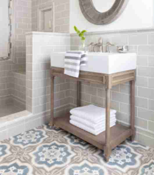 Modern farmhouse bathroom with subway wall tile and brown and blue encaustic floor tile.