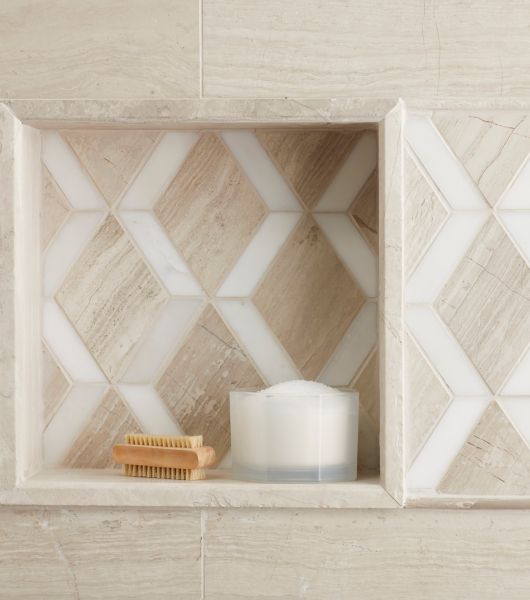 Detailed view of shower niche in natural stone.  Colors are taupe, grey and white.  Shower items are stored in niche.