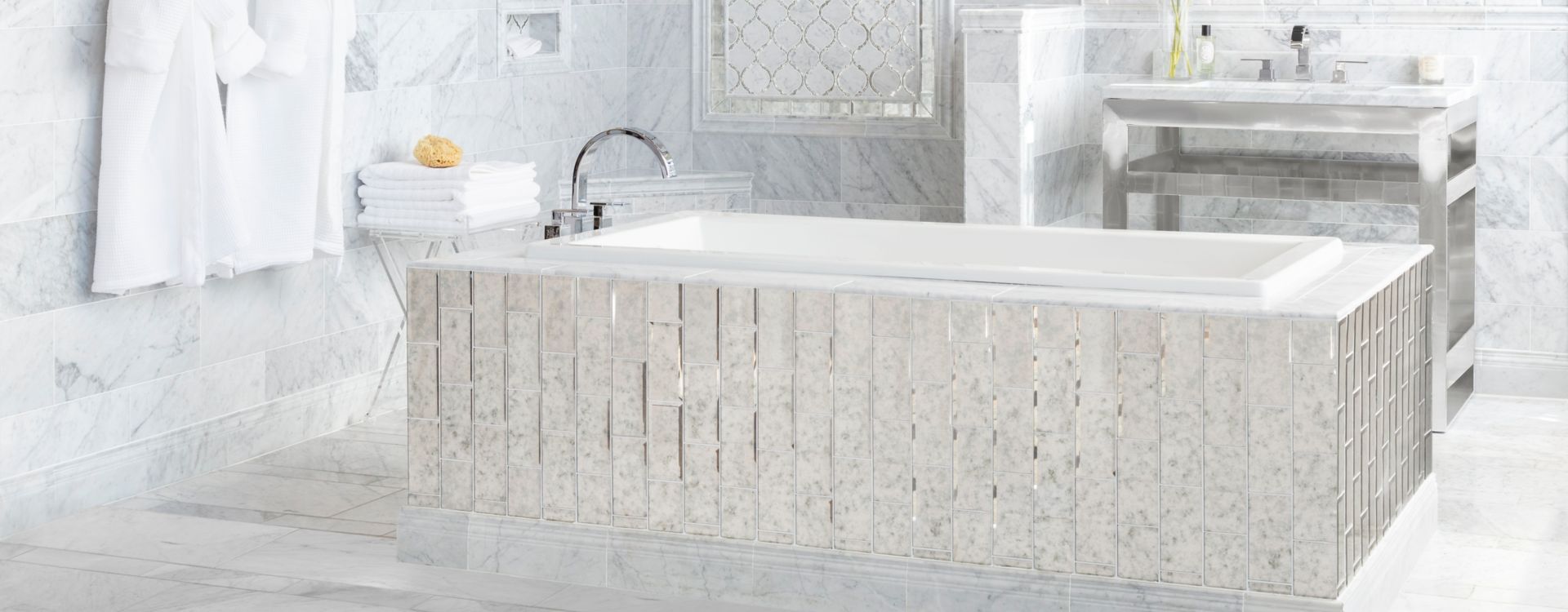 Elegant bathroom with white marble tile and antique mirror accents.