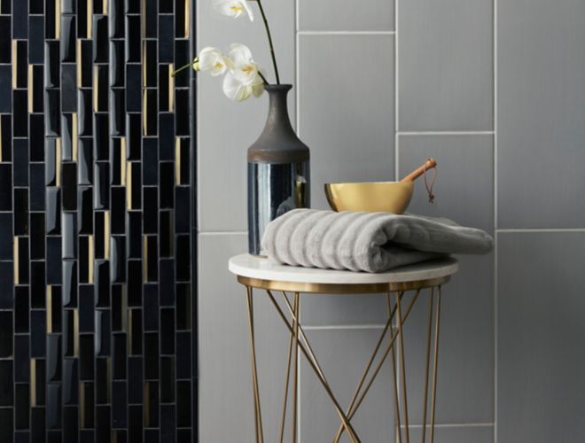 Contemporary shower wall with grey large-format tile and black and gold glass mosaic.