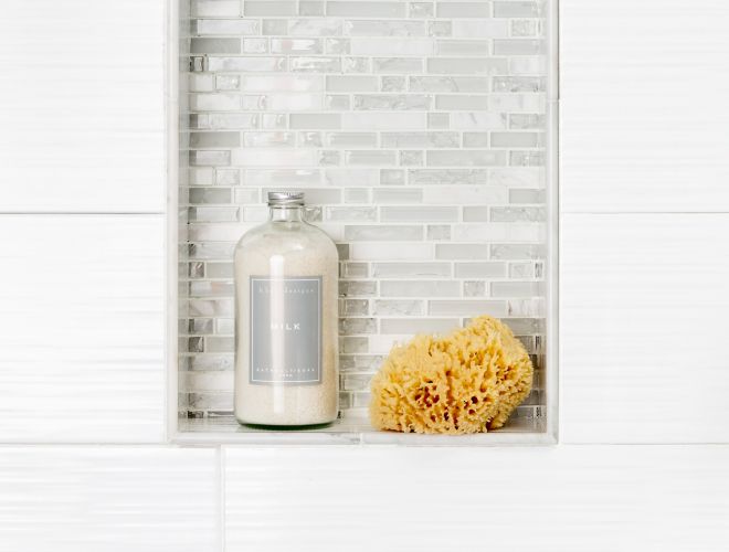 White tiled shower wall with recessed shelf. 