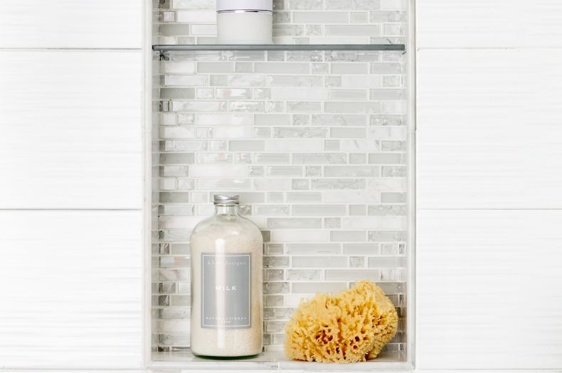 White tiled shower wall with recessed shelf. 