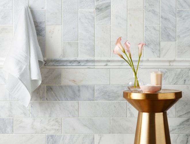 White and grey marble tiled shower wall with gold accent table.