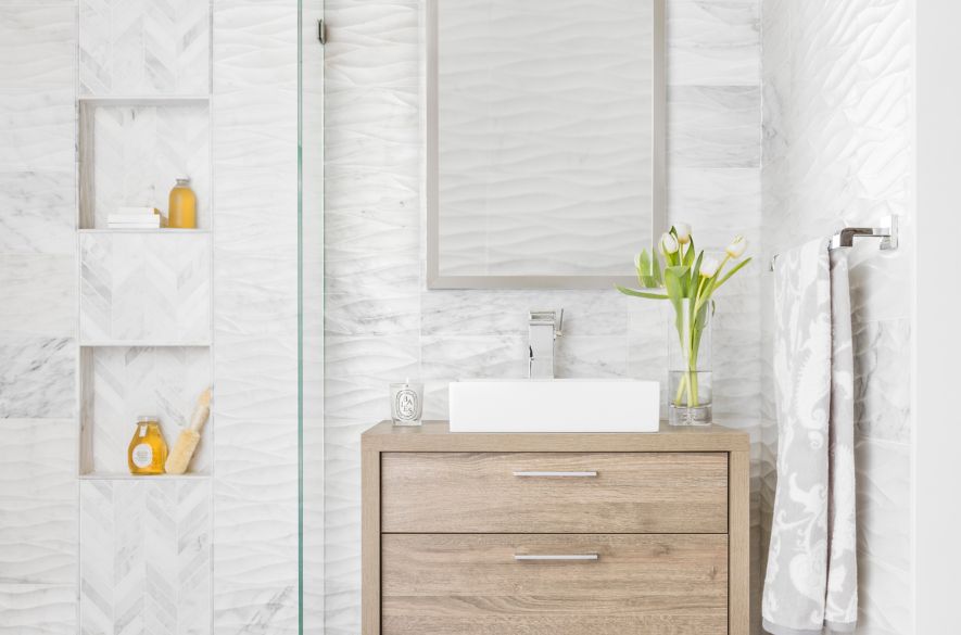 Bathroom with white carrara marble walls and warm wood accents.