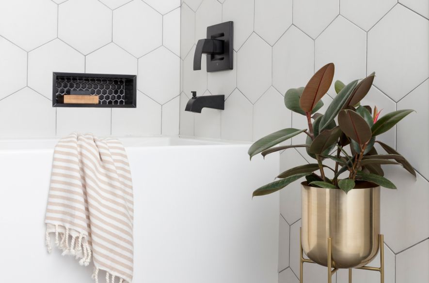 Bathroom area with  large hexagon tile on wall and small black hexagon tile in recessed niche and large profile grey tile on floor.