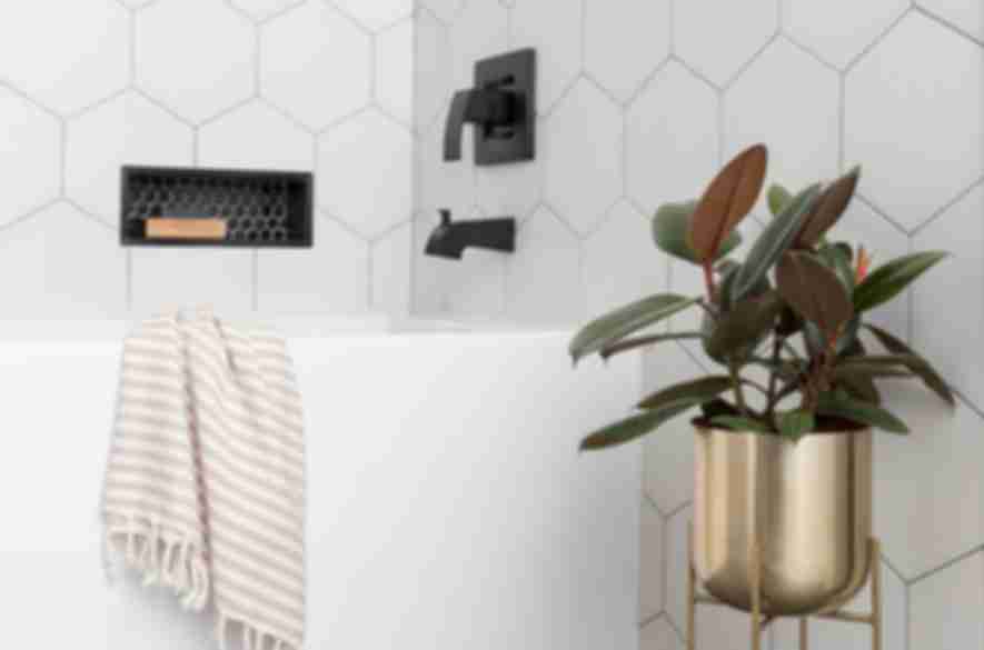 Bathroom area with  large hexagon tile on wall and small black hexagon tile in recessed niche and large profile grey tile on floor.