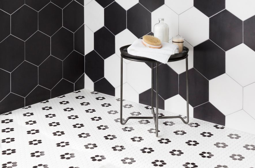 A shower with large black-and-white hexagon tile walls and small black-and-white hexagon floral patterned floor.