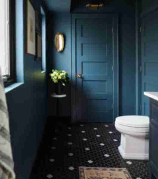 This cool blue bathroom features a black and white cross-shaped tile floor. 