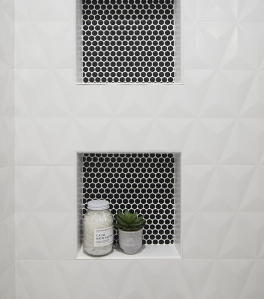 White sculptural tile walls with two shower niches featuring black penny round tile.