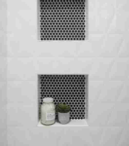 White sculptural tile walls with two shower niches featuring black penny round tile.