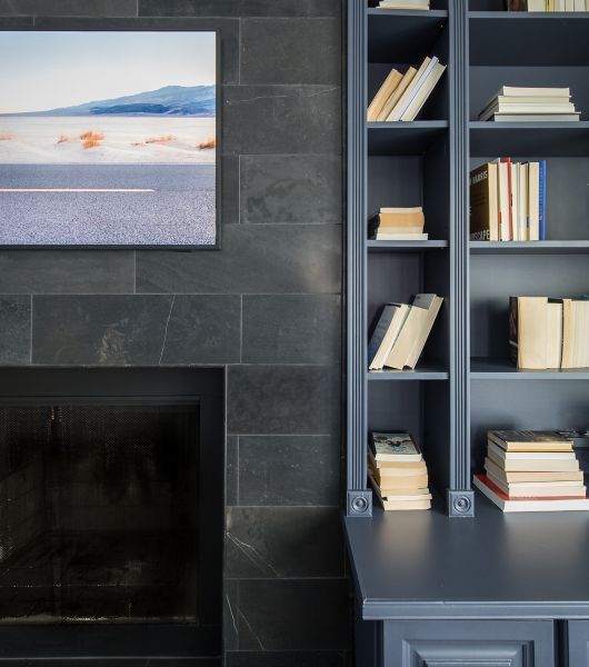 A living room fireplace is tiled with dark honed limestone tiles. The tile extends up to the ceiling and is also used on the hearth.