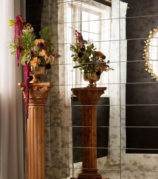 This room features a wall covered in large-format, silver mirrored tiles with an antique patina finish. The tiles are oriented horizontally and stacked in aligned rows.