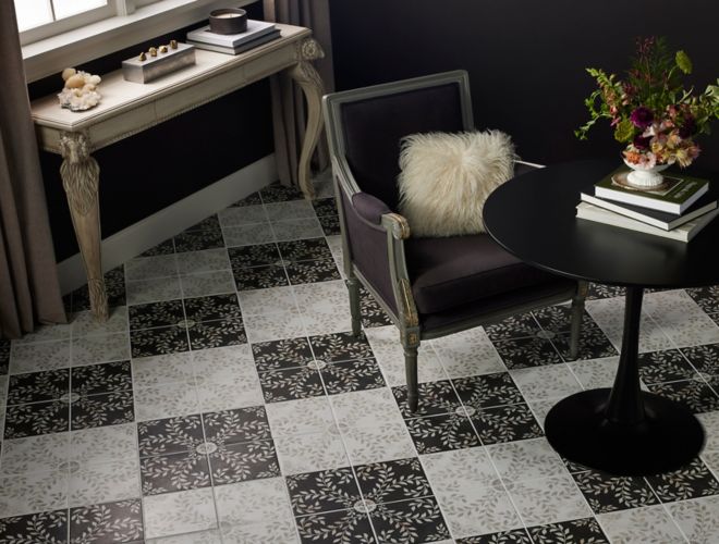 Black and White patterned porcelain tiles making creating a checkerboard floor with a lounge chair and small circular table.
