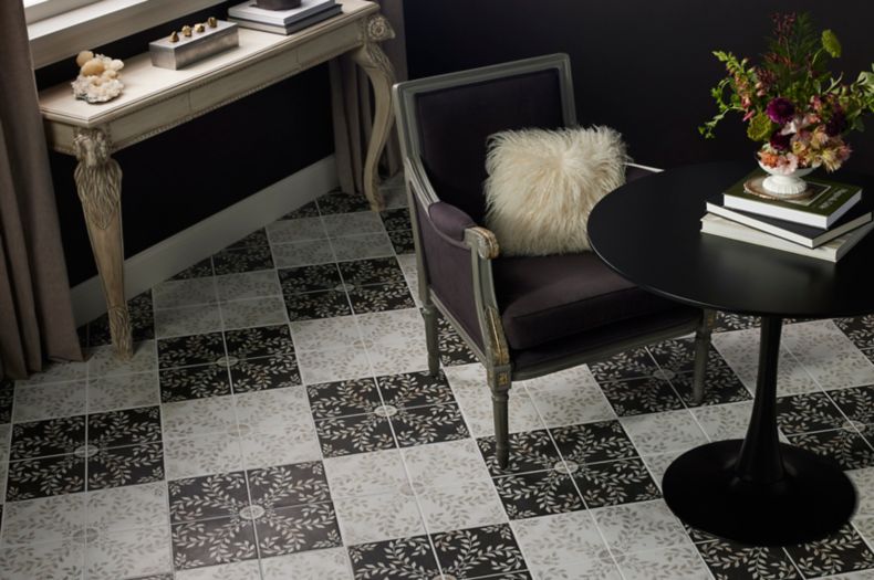 Black and White patterned porcelain tiles making creating a checkerboard floor with a lounge chair and small circular table.