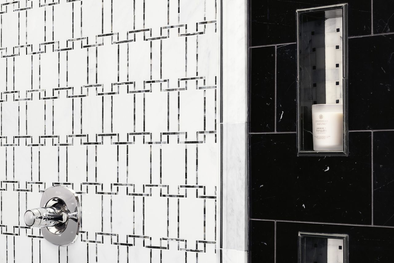 Walk in shower area with a close up view of niches and decorative mosaic tile made of natural stone marble, black and white is the color scheme.  